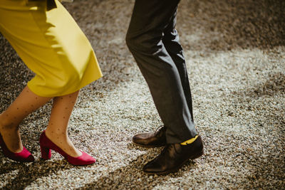 Low section of man and woman standing on yellow shoes