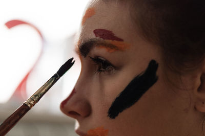 Close-up of young woman applying face paint