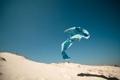 Low angle view of towel paragliding against clear sky