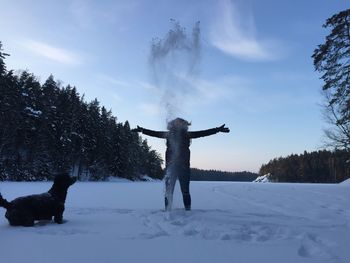 Woman standing on snow covered trees against sky