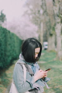 Woman holding umbrella while standing by plants