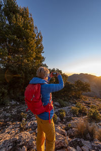 Woman hiking and taking a picture of the puig campana mountains.