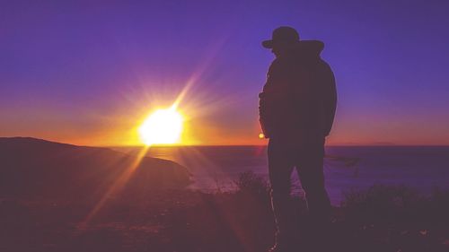 Silhouette of man standing on beach at sunset