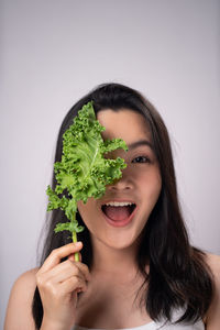 Portrait of woman holding ice cream against white background