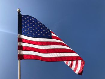 Low angle view of flag against blue sky