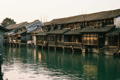 Houses by lake against clear sky