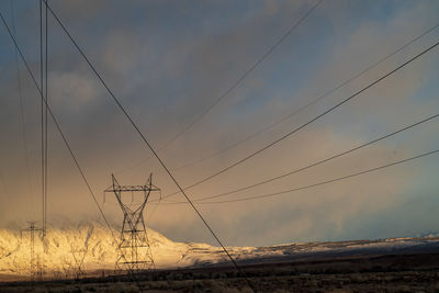 Electricity pylon on field against sky