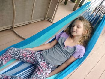 High angle view of smiling girl sleeping in hammock at porch