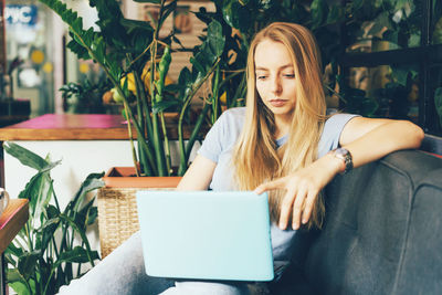 Young girl blonde manager in cozy coworking on the couch with a laptop. millennial generation