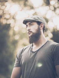 Low angle view of young man looking away against trees