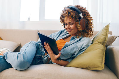 Young woman using phone while sitting on sofa at home