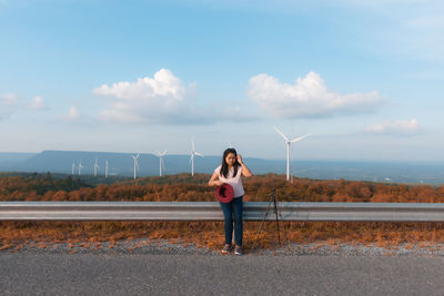 Full length of woman standing on road against sky