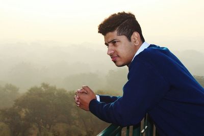 Side view of young man against sky