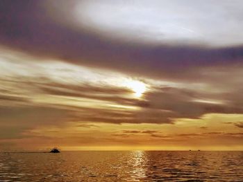 Scenic view of sea against dramatic sky during sunset