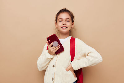 Portrait of young woman holding book against pink background