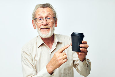 Portrait of senior man holding coffee cup against white background