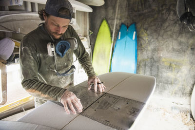 Surfboard shaper measuring a new design