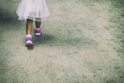 Low section of girl walking on footpath