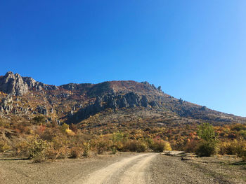 Road by mountain against clear blue sky