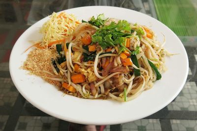 Pad thai with prawns served in plate on table