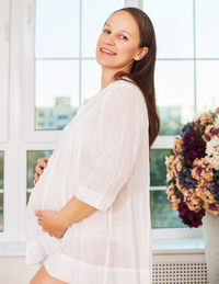 Pregnant woman by window at home