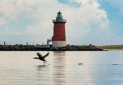 Lighthouse by sea against sky