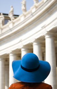 Rear view of woman wearing hat standing against historic building