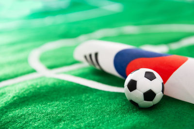 Close-up of small soccer ball with flag on green textile