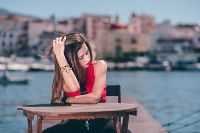 Woman sitting on pier over sea