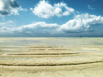 Scenic view of beach against cloudy sky