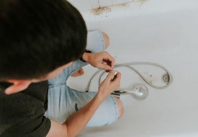 A young man wraps tow around the nut of a bathroom faucet.