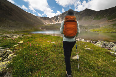 Woman with a backpack walks near the mountains and a blue lake. travel and hobby concept