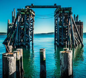 Wooden posts on pier over sea against blue sky