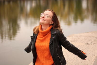 Young woman smiling by the lake, enjoying herself