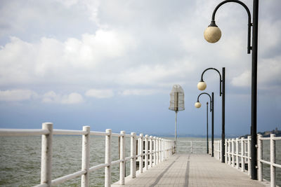 Street light by sea against sky