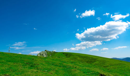 Landscape of green grass and rock hill in spring with beautiful blue sky and white clouds. 