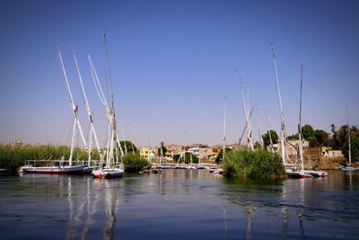 Boats moored on lake against clear sky in city