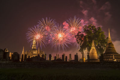 Firework display over building against sky at night