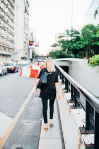 Rear view of woman walking on city street