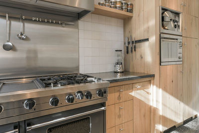 Modern interior of spacious kitchen with wooden cupboards and new appliances in flat