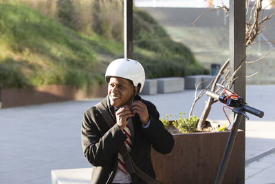 Businessman with helmet and electric scooter resting outdoors person