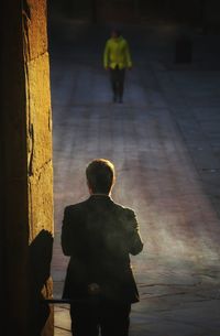 Rear view of man standing on footpath