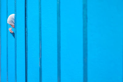 Woman wearing hijab standing amidst blue wall