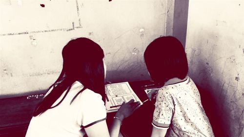 Rear view of friends standing against wall