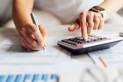 Midsection of woman using calculator at table