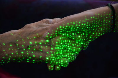 Close-up of hand holding illuminated light over black background