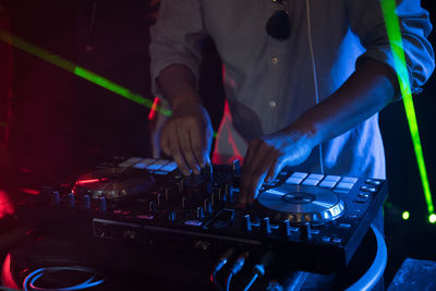 Midsection of man operating sound mixer at nightclub