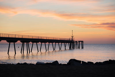 Pier over sea against sky during sunset