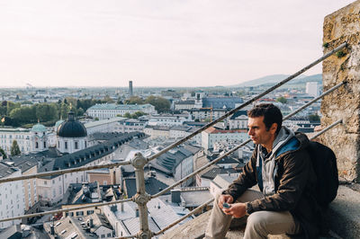 Man sitting on steps against cityscape