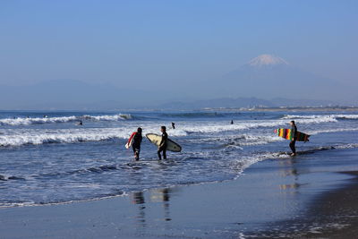 People with surfboard walking on beach